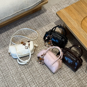Group view of four colorful mini Boston bags with vintage beaded charms on a woven rug