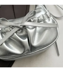 Close-up of metallic silver pleated shoulder bag featuring a stylish bow and soft texture