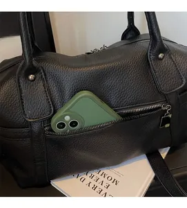 Detail of black pebbled leather tote showing front zipper pocket with a phone inside