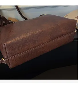 Detail view of coffee brown tote bag showing soft pebble leather texture and gold metal rings
