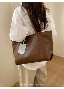 Detail of large dark brown retro tote bag featuring a cute embossed animal charm
