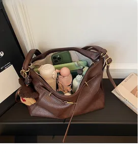 Detail view of large brown pebble leather tote bag with spacious interior and bear charm