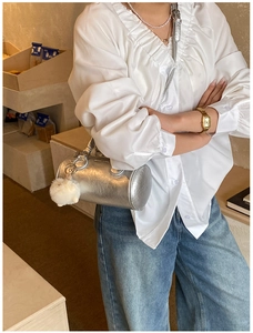 Fashionable silver baguette bag styled with white satin blouse and blue denim jeans