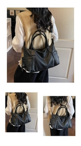 Detail of black textured faux leather tote bag with dual handles and adjustable strap