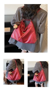 Close-up of red pebbled leather tote bag with gold hardware and a cute brown bear charm