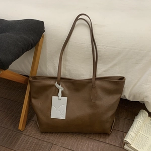 Close-up of deep brown leather tote bag with fine texture and white decorative tag
