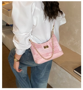 Detailed view of pink plaid underarm bag with gold chain and metal twist lock closure