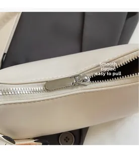 Detailaufnahme des glatten Silber-Reißverschlusses und cremefarbenen Leders der Tasche