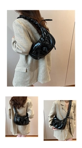 Close-up of black glossy pleated underarm bag featuring bow details and gathered strap