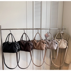 Detailed row of five leather tote bags in various colors hanging on a metal rack