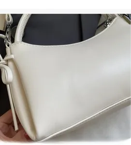 Detailaufnahme der glatten cremefarbenen Ledertextur und des Knotendekors der Tasche