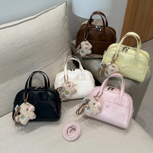 Detail view of colorful mini Boston bags with cute sheep pendants on a grey sofa