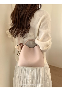 Minimalist pink pebble leather bucket bag with a cute brown plush bear charm detail
