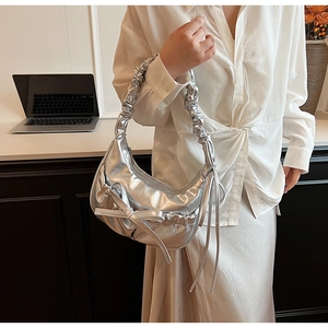 Detail view of silver metallic crescent bag with bow decoration and ruched handle