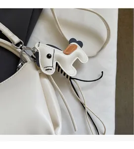 Detail einer weißen Lederhandtasche mit einem stilvollen braun-schwarzen Pferdeanhänger
