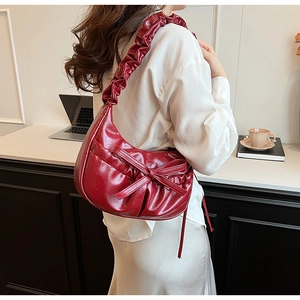 Detail of burgundy ruched shoulder bag with bow knot and glossy pleated texture finish