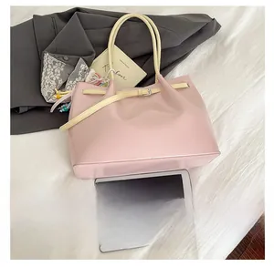 Top view of pink glossy tote bag with yellow straps on soft white fabric background