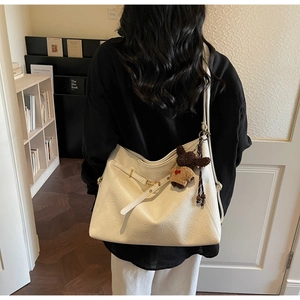 Detail of cream large tote bag with litchi texture PU leather and brown bear charm