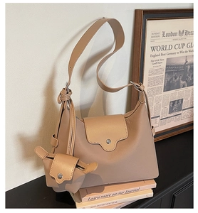 Detail of a khaki leather tote bag with a mini pouch accessory on vintage books