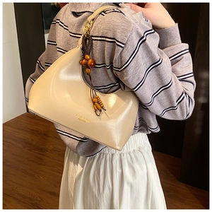 Detail of beige glossy leather hobo bag with wood bead charm and fashion logo print