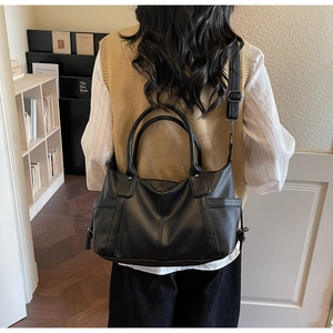 Model view showing the back side of a black pebbled leather tote bag with side pockets