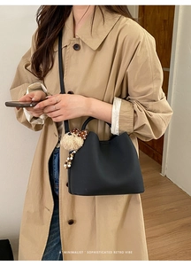 Detail of black leather bucket bag with cute brown polka dot plush bear charm accessory