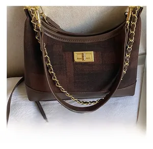 Detail view of large canvas tote bag featuring brown grid pattern and gold turn-lock