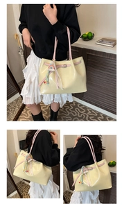 Close-up of cream faux leather tote bag with pink handles and rainbow charm detail