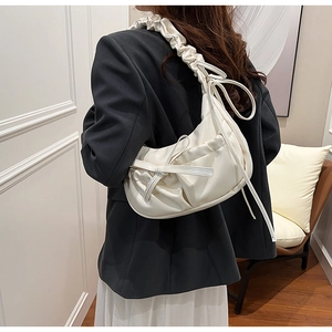 Detail of white PU leather pleated underarm bag with decorative bow and gathered strap