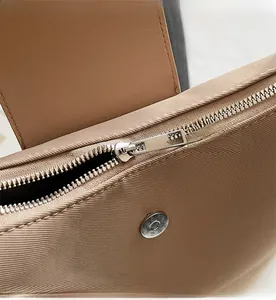 Detail of smooth metal zipper and magnetic buckle on textured brown tote bag fabric