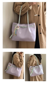 Detail view of large purple tote bag with green strap and rainbow love charm