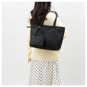 Gros plan d'un grand sac cabas en nylon noir avec une mini pochette sur une femme