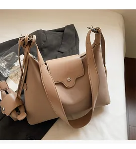 Macro shot of stylish beige underarm bag featuring a wide strap and silver magnetic closure