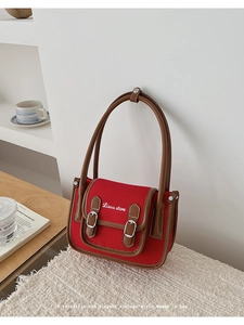 Detail of red canvas bag with brown leather trim and elegant white cursive embroidery