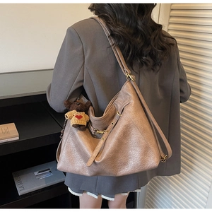 Detail view of large brown tote bag with cute bear charm and adjustable shoulder strap