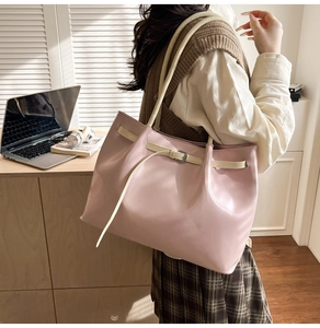 Detailed view of pink tote bag with contrast cream straps and chic metal hardware
