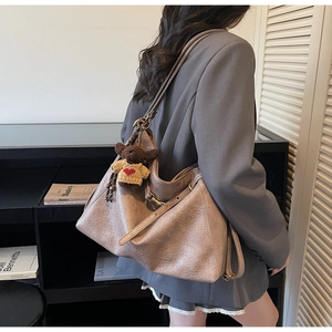 Back view of model wearing a large dusty pink lychee leather tote bag with a bear charm