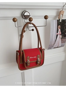 Detail view of red canvas handbag with brown leather trim and vintage metal buckle strap