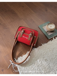 Detailed macro view of the vintage red canvas bag with brown leather trim and buckles