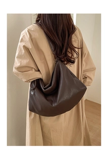 Close-up of deep brown leather tote bag with subtle logo tag and premium grain texture