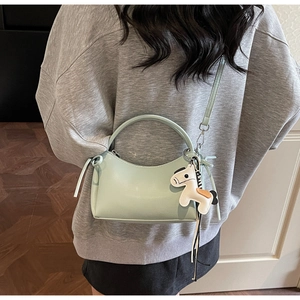 Detail view of mint green bucket bag featuring a smooth leather finish and horse charm