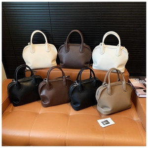 Detailed close-up of multi-color leather shell tote bags displayed on a vintage leather bench