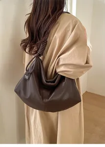 Detail of a dark brown hobo bag featuring a knotted shoulder strap and textured leather