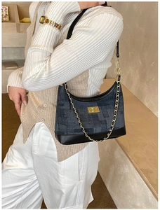 Retro denim shoulder bag with gold chain and buckle on a model in a minimalist setting
