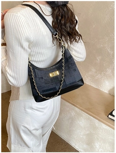 Detail of grey textured hobo bag with gold chain and metal lock on model shoulder