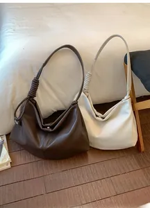 Detail of hobo shoulder bags in brown and beige with woven knot handle and magnetic closure