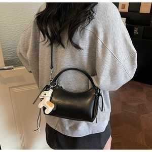 Détail d'un sac bandoulière demi-lune en cuir noir avec un charmant mouton blanc