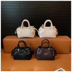 Four women's lychee leather handbags in white, beige, black, and dark red on a leather bench