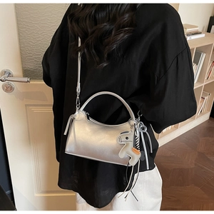 Details der silbernen Metallic-Baguette-Tasche mit Pferdeanhänger und Quastenakzent