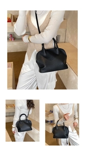 Detail of black pebbled leather handbag featuring twin handles and a crossbody strap